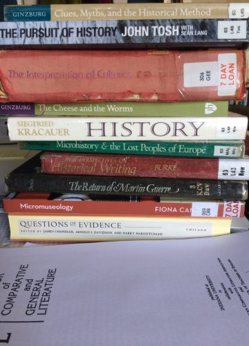 A pile of academic books and papers on a desk